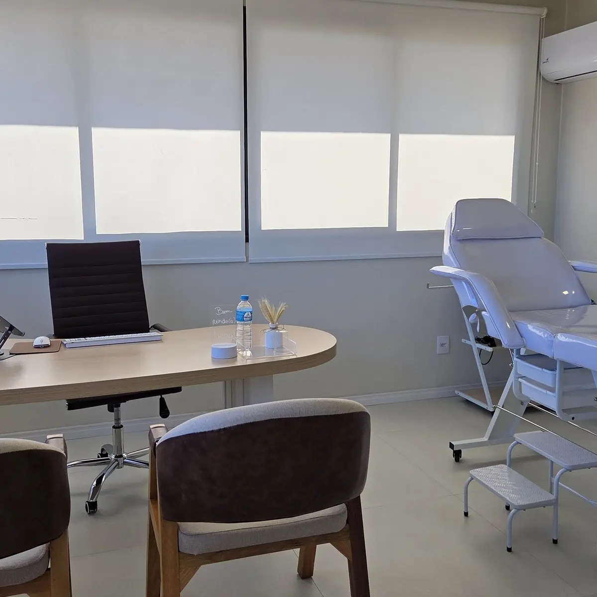Sala de atendimento da clínica, com mesa de consulta e maca